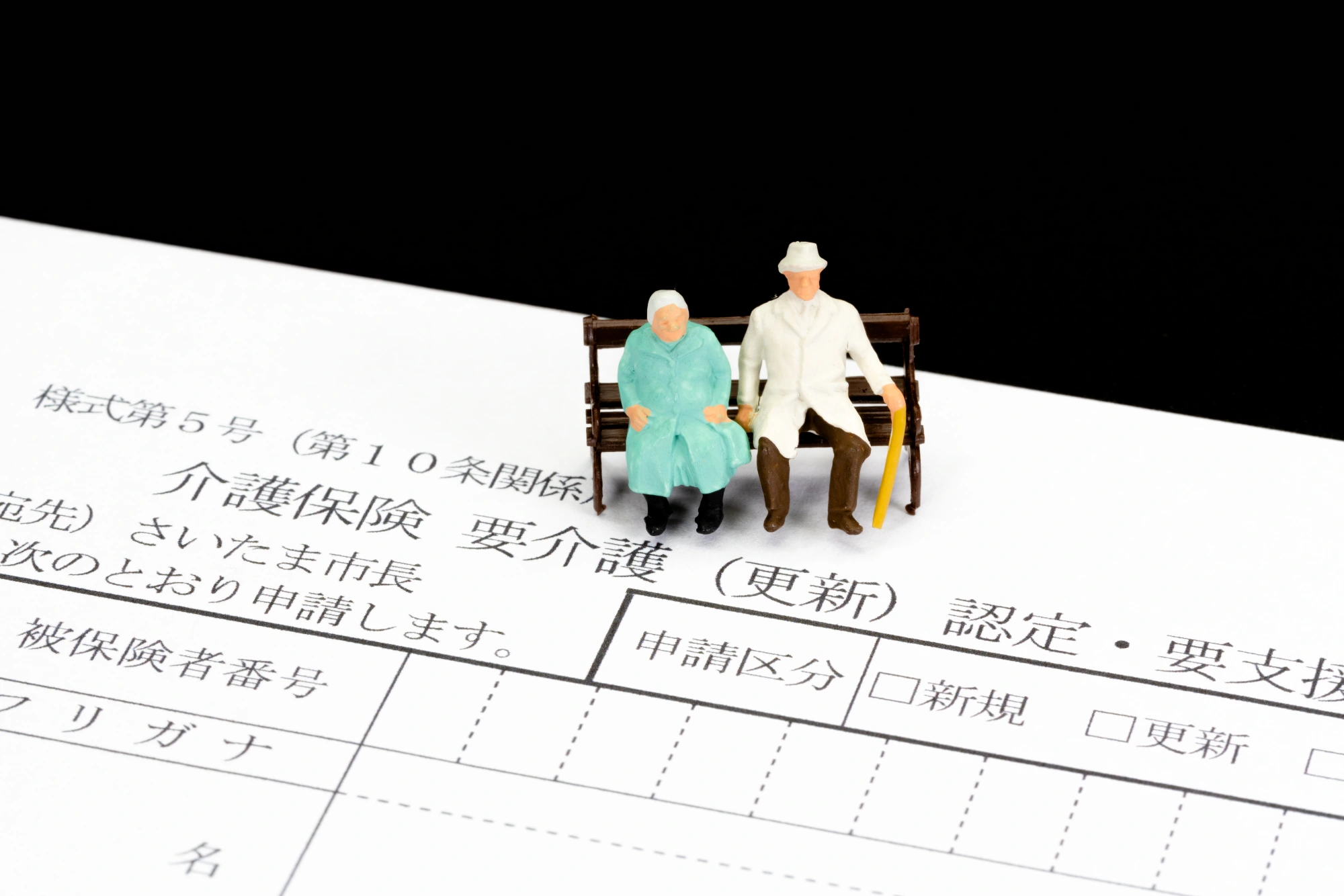 要介護の書類の上にある老夫婦のフィギュア